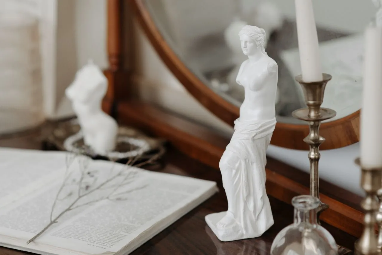 Small classical sculpture among books and silver objects