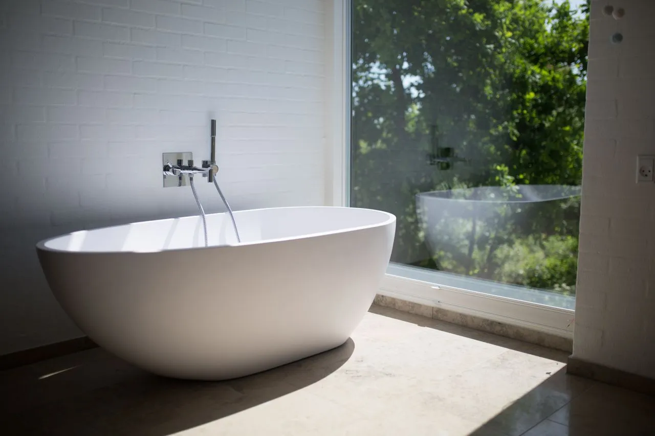 Freestanding bath beside a private garden window